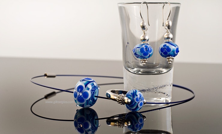 Ensemble "Meeresblüte 2", bestehend aus 1 Fingerring, 2 Ohrhänger und Halsreif mit blauen Murano-Glasperlen. Ensemble "Meeresblüte 2", bestehend aus 1 Fingerring, 2 Ohrhänger und Halsreif mit blauen Murano-Glasperlen.