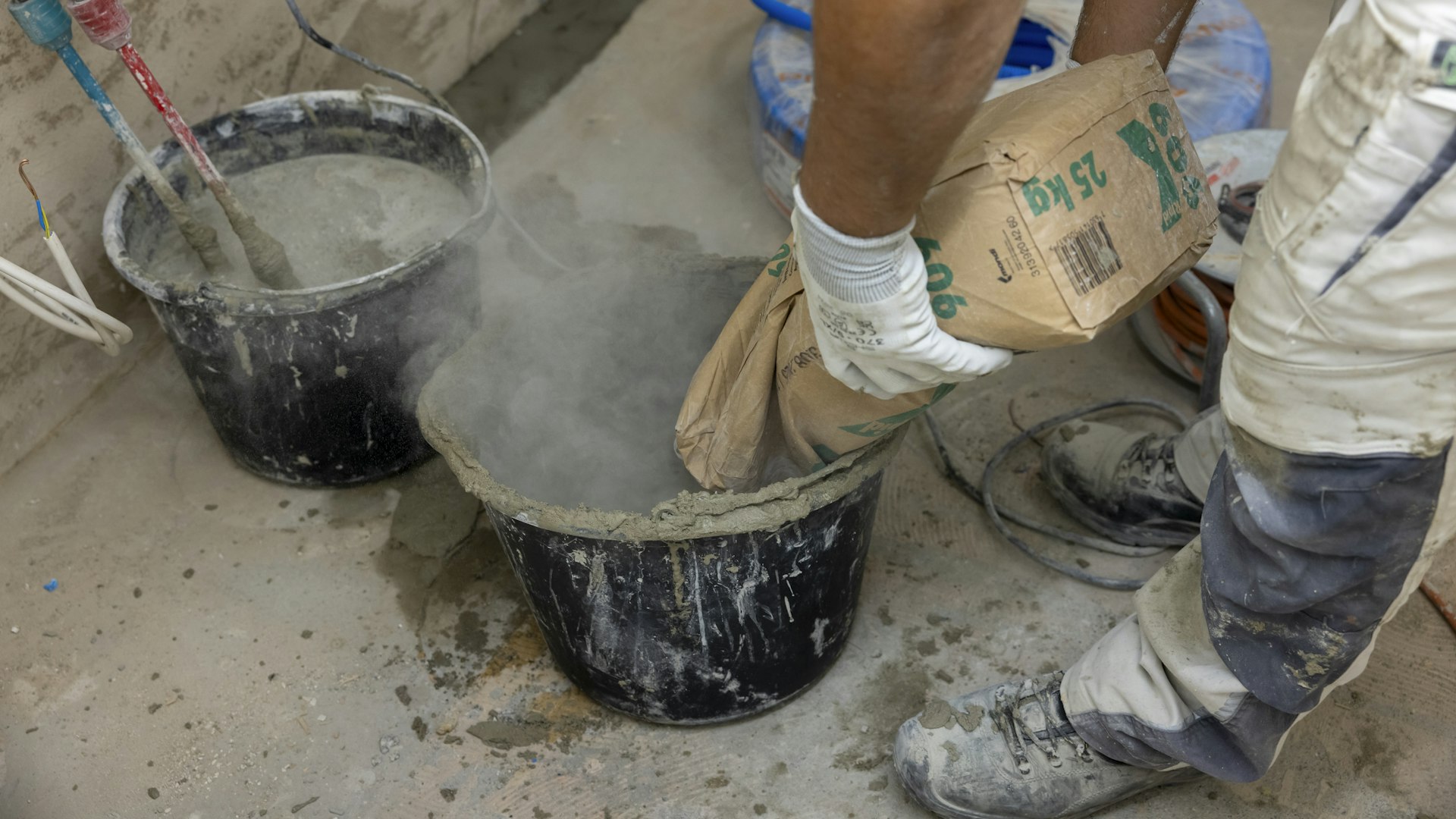 Ein Handwerker mischt Beton an, um die Wände zu verputzen. Ein Handwerker mischt Beton an, um die Wände zu verputzen.
